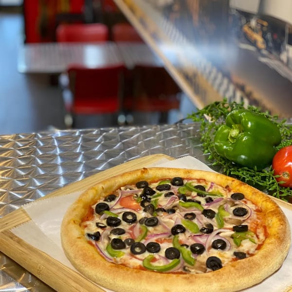 King's Pizza veggie pizza with olives, peppers, onions, and mushrooms on a wooden board.