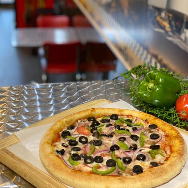 King's Pizza veggie pizza with olives, peppers, onions, and mushrooms on a wooden board.