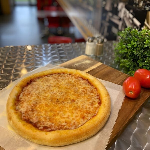 King's Pizza cheese pizza with two tomatoes and greenery on a wooden board.